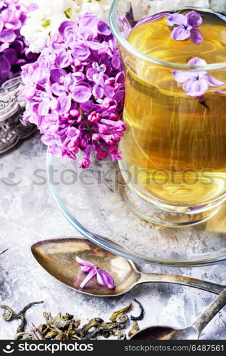 Tea with lilac flavor. Cup of fragrant spring tea and a branch of blossoming spring lilac.Herbal tea