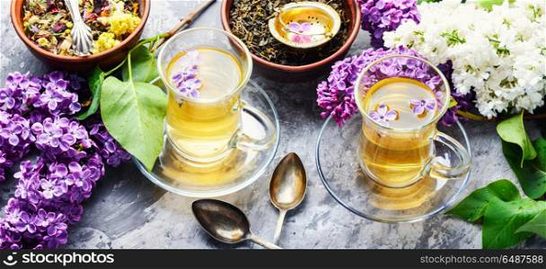 Tea with lilac flavor. Cup of fragrant spring tea and a branch of blossoming spring lilac.Green tea.Lilac flowers