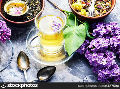 Tea with lilac flavor. Cup of fragrant spring tea and a branch of blossoming spring lilac.Herbal tea