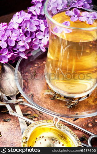 Tea with lilac flavor. Cup of fragrant spring tea and a branch of blossoming spring lilac.Herbal tea