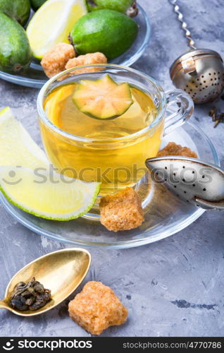 Tea with lime and feijoa. Hot tea with feijoa and lime on blue background