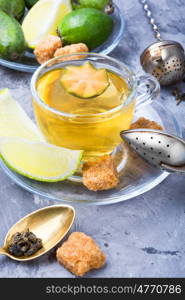 Tea with lime and feijoa. Hot tea with feijoa and lime on blue background