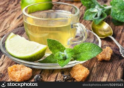 Tea with mint and lemon. Glass cup with tea with lemon and mint on a saucer