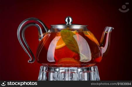Tea with mint and lemon in a transparent teapot on a gray background. Isolated with backlight. Mint tea in a transparent teapot