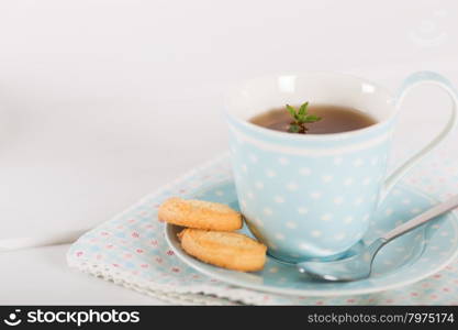 Tea with mint cookies served in a porcelain cup and saucer