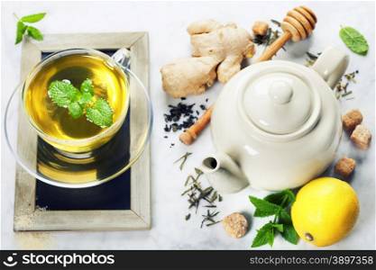 Tea with mint, ginger and lemon on marble background