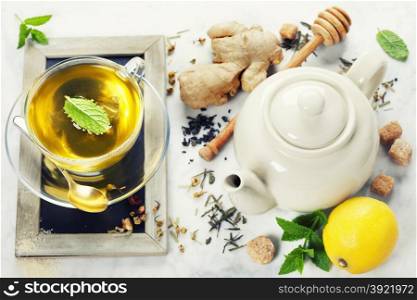 Tea with mint, ginger and lemon on marble background