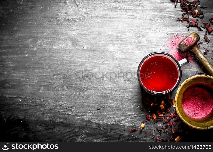 tea with pomegranate crushed in a mortar. On a black wooden background.. tea with pomegranate crushed in a mortar.