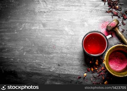 tea with pomegranate crushed in a mortar. On a black wooden background.. tea with pomegranate crushed in a mortar.