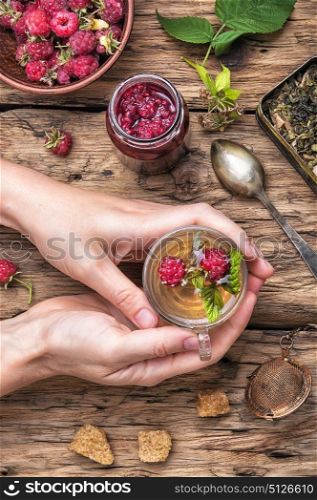 Tea with raspberries. Tea cup with raspberry warming tea in hands