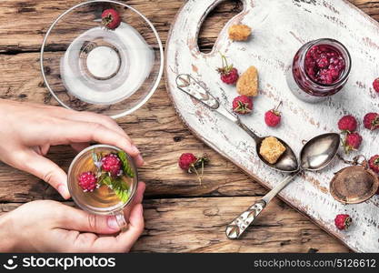 Tea with raspberries. Tea cup with raspberry warming tea in hands