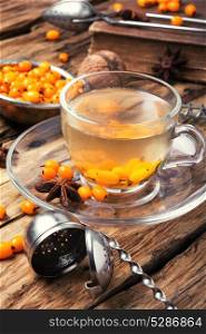 tea with sea-buckthorn. cup with healing tea with berries of sea-buckthorn on wooden retro background