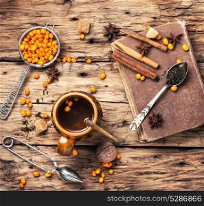 tea with sea-buckthorn. cup with healing tea with berries of sea-buckthorn on wooden retro background