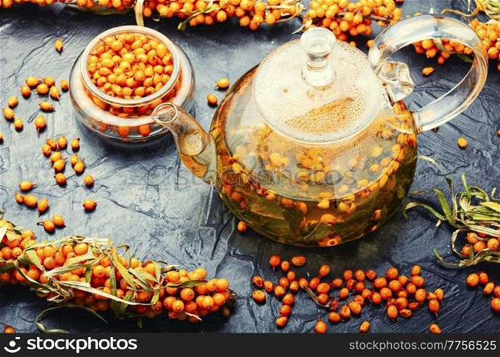 Tea with sea buckthorn. Delicious medicinal tea from autumn berries in glass teapot. Seasonal healing sea buckthorn tea