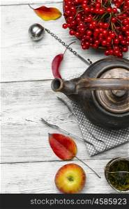 Tea with viburnum. Stylish earthenware teapot with tea from medicinal autumn berries tea with viburnum
