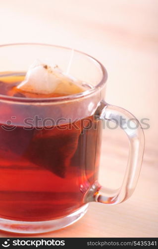 teabag in cup with tea on wooden table
