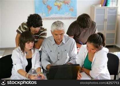 Teacher and a group of pupils sitting round a laptop