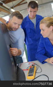 teacher and apprentices fixing a television