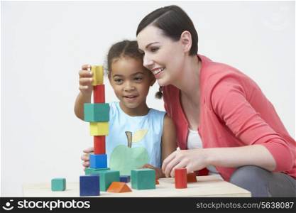 Teacher And Pre-School Pupil Playing With Wooden Blocks