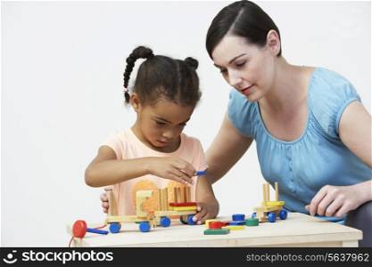 Teacher And Pre-School Pupil Playing With Wooden House