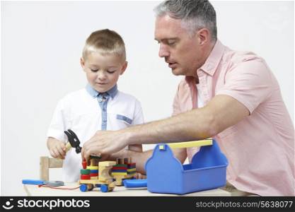 Teacher And Pre School Pupil Playing With Wooden Tools