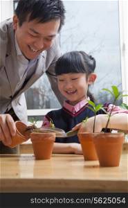 Teacher and schoolgirl planting plants into flower pots