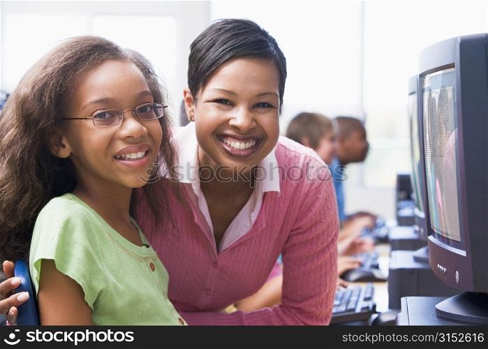 Teacher and student at computer terminal with students in background (selective focus/high key)