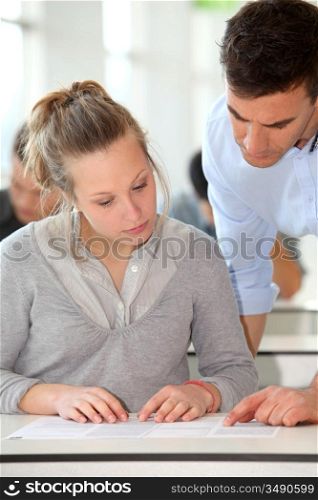 Teacher assisting student girl in class