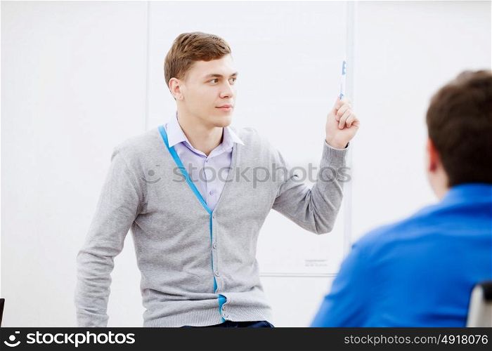 Teacher at lesson. Young teacher in classroom standing in front of class