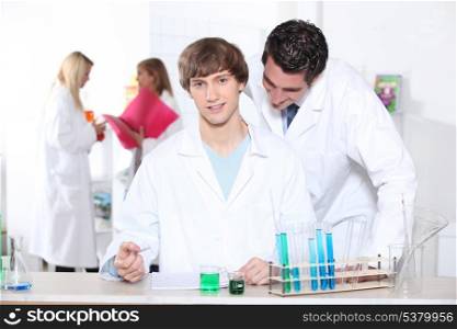 Teacher checking students work in laboratory