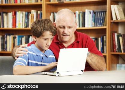 Teacher helping a student use a netbook computer in the school library.