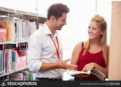 Teacher Helping College Student With Studies In Library