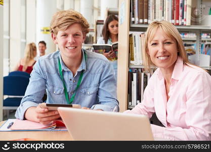 Teacher Helping College Student With Studies In Library