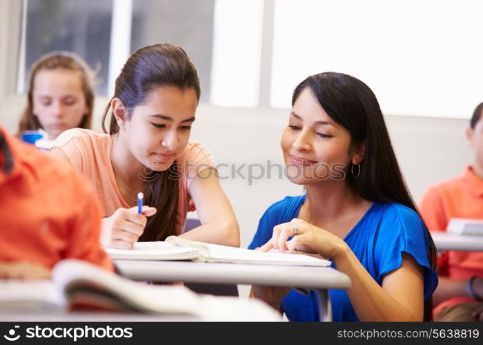 Teacher Helping Female High School Student In Classroom