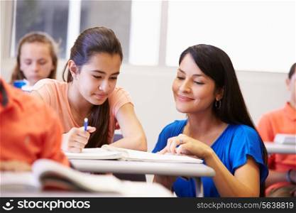 Teacher Helping Female High School Student In Classroom