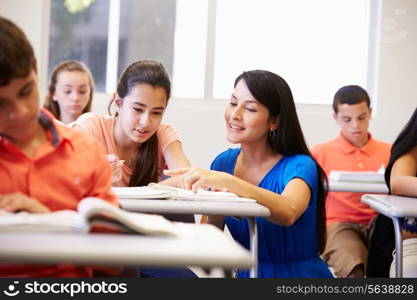 Teacher Helping Female High School Student In Classroom