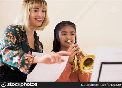 Teacher Helping Female Student To Play Trumpet In Music Lesson