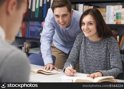 Teacher Helping Female Teenage Pupil In Class