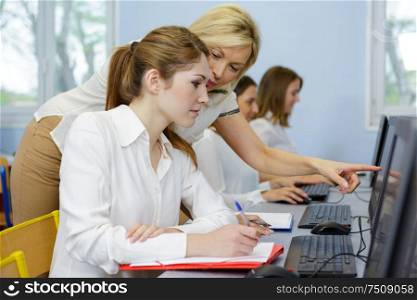 teacher helping her student in computer class