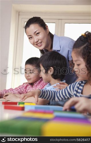 Teacher Helping Her Students and Looking at Camera