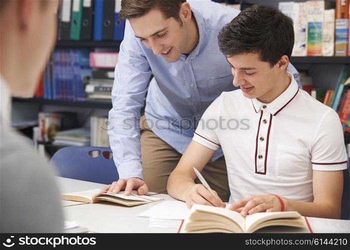 Teacher Helping Male Pupil In Class