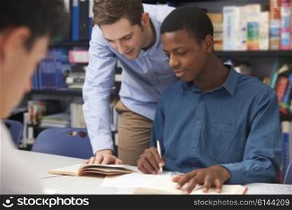 Teacher Helping Male Student In Classroom