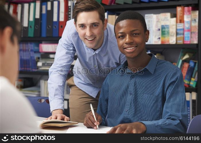 Teacher Helping Male Teenage Pupil In Class