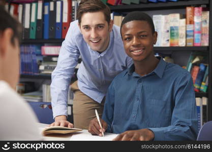 Teacher Helping Male Teenage Pupil In Class