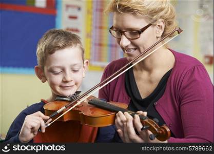 Teacher Helping Pupil To Play Violin In Music Lesson