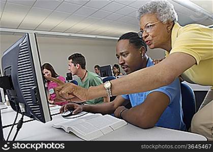 Teacher helping student in computer class