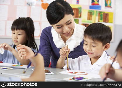 Teacher Helping Students During Art Class In Chinese School Classroom