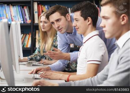 Teacher Helping Students Working At Computers
