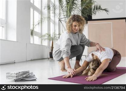 teacher helping woman yoga
