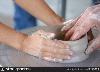 teacher helps a child to potting a jar on spin dish.
